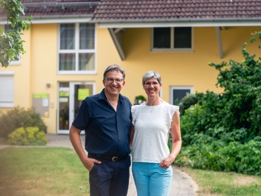 Christine und Norbert Häckler stehen nebeneinander vor einem gelben Gebäude des Ferienhofs
