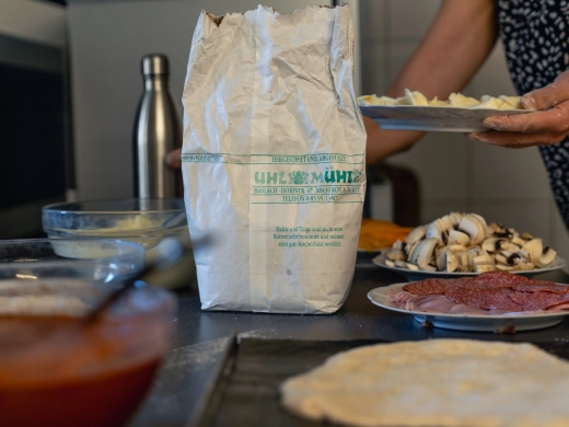 Zutaten fürs Pizza backen auf der Arbeitsfläche: Tomatensauce, Belag und ausgerollter Teig