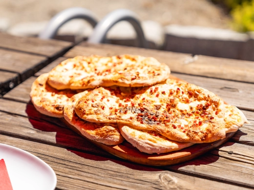 Frisch gebackene Pizzafladen gestapelt auf einem Holztisch im Freien