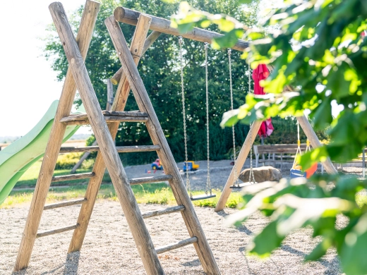 Schaukelgerüst aus Holz mit Sandkasten im Hintergrund