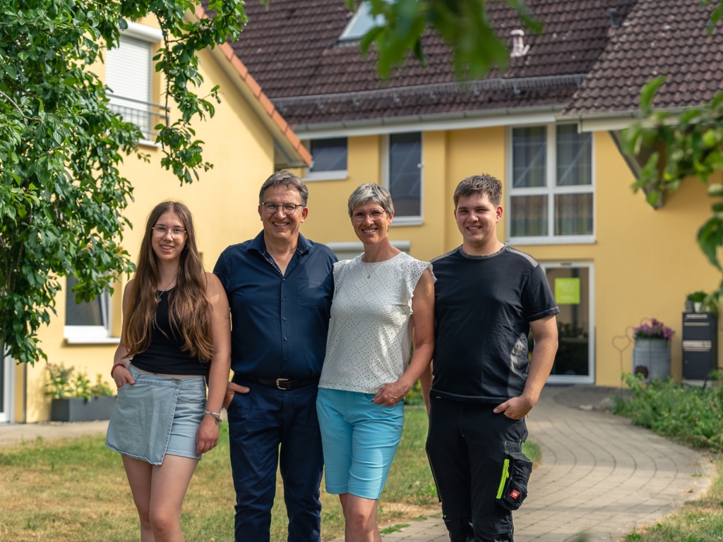 Familie Häckler steht zu viert vor einem gelben Gebäude des Ferienhofs