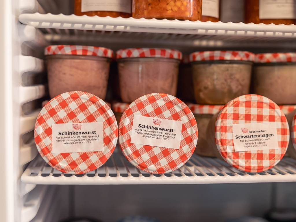 Hausgemachte Schinkenwurst und Schwartenmagen in Gläsern mit rot-weiß karierten Deckeln im Hofladen