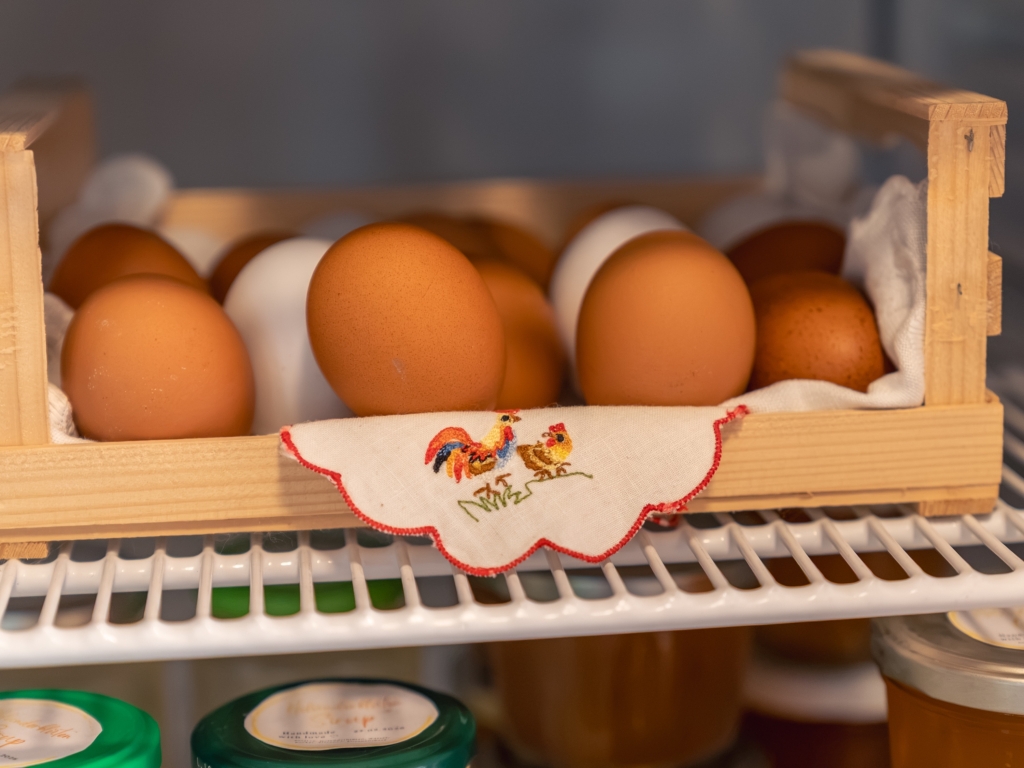 Frische Eier in einer Holzkiste mit verziertem Schild im Kühlschrank des Hofladens