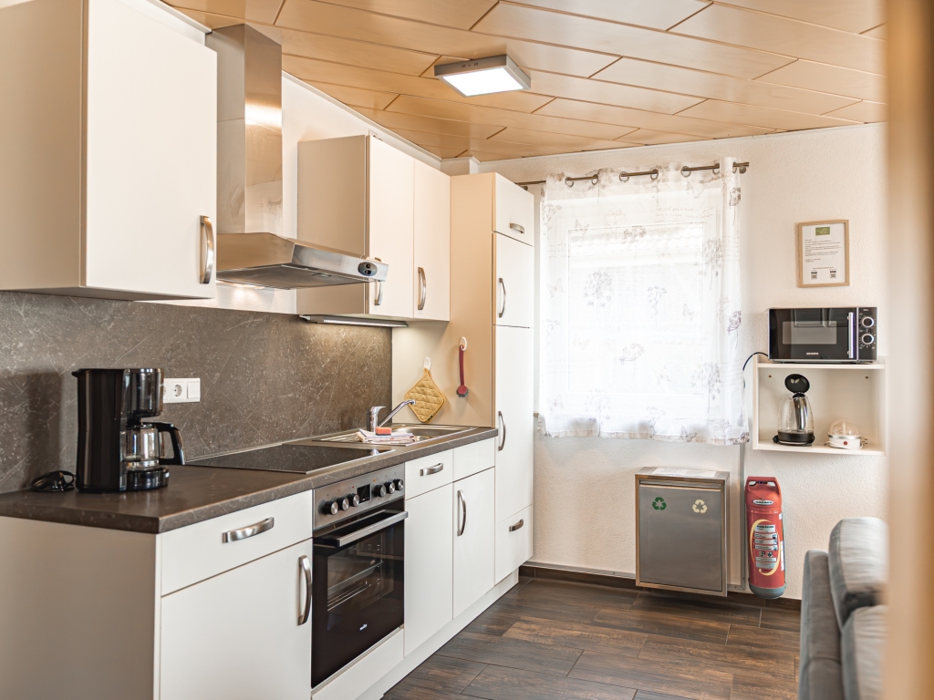 Ferienwohnung 10: Sitzplatz mit Tisch, Stühlen und Pflanze, umgeben von dichtem Grün