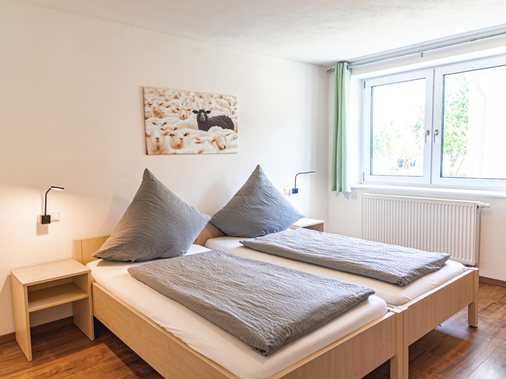 Ferienwohnung 1: Schlafzimmer mit zwei zusammengestellten Betten, Nachttischen und Leselampen