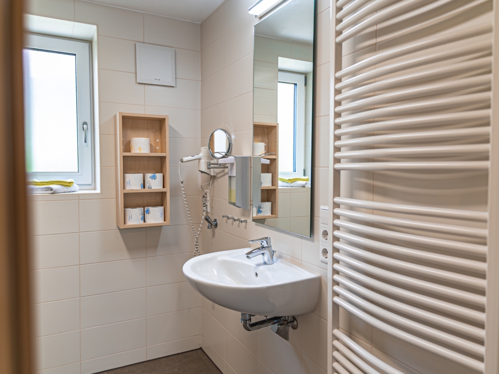 Ferienwohnung 2: Badezimmer mit Waschbecken, Handtuchheizkörper, Wandregal und Spiegel