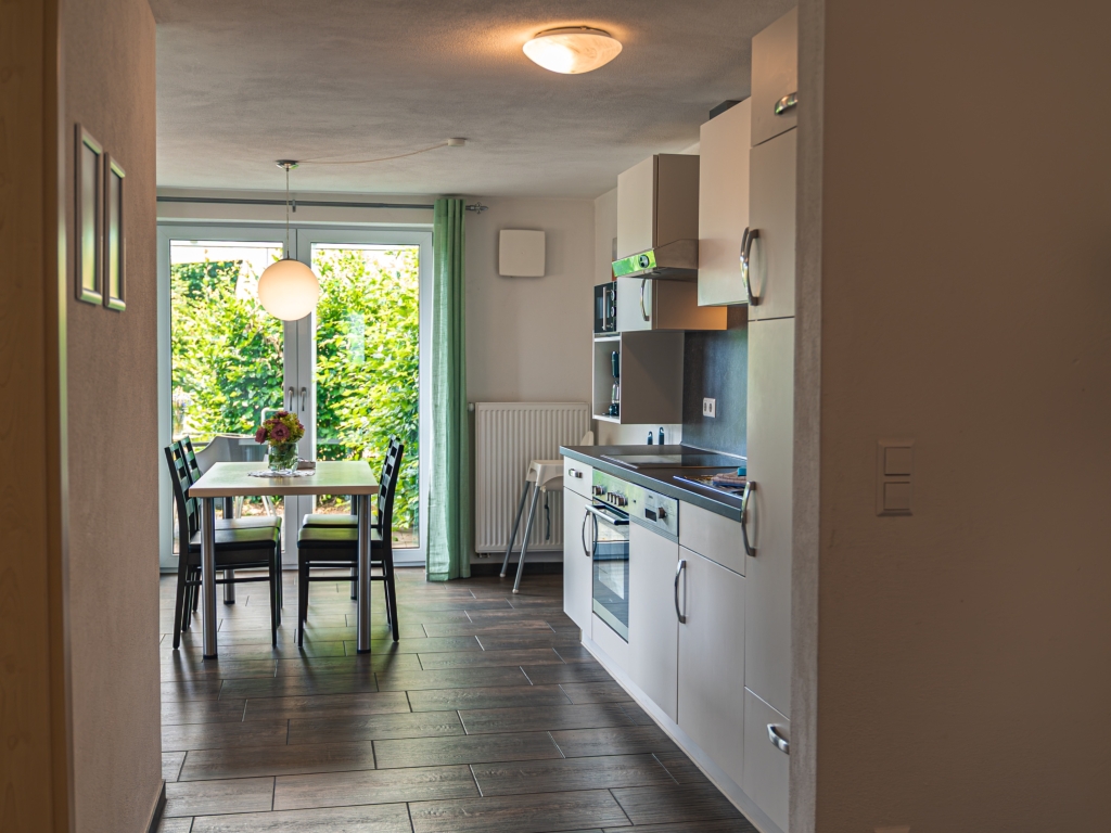 Ferienwohnung 2: Blick durch die Wohnküche mit Küchenzeile und Esstisch zur Terrassentür
