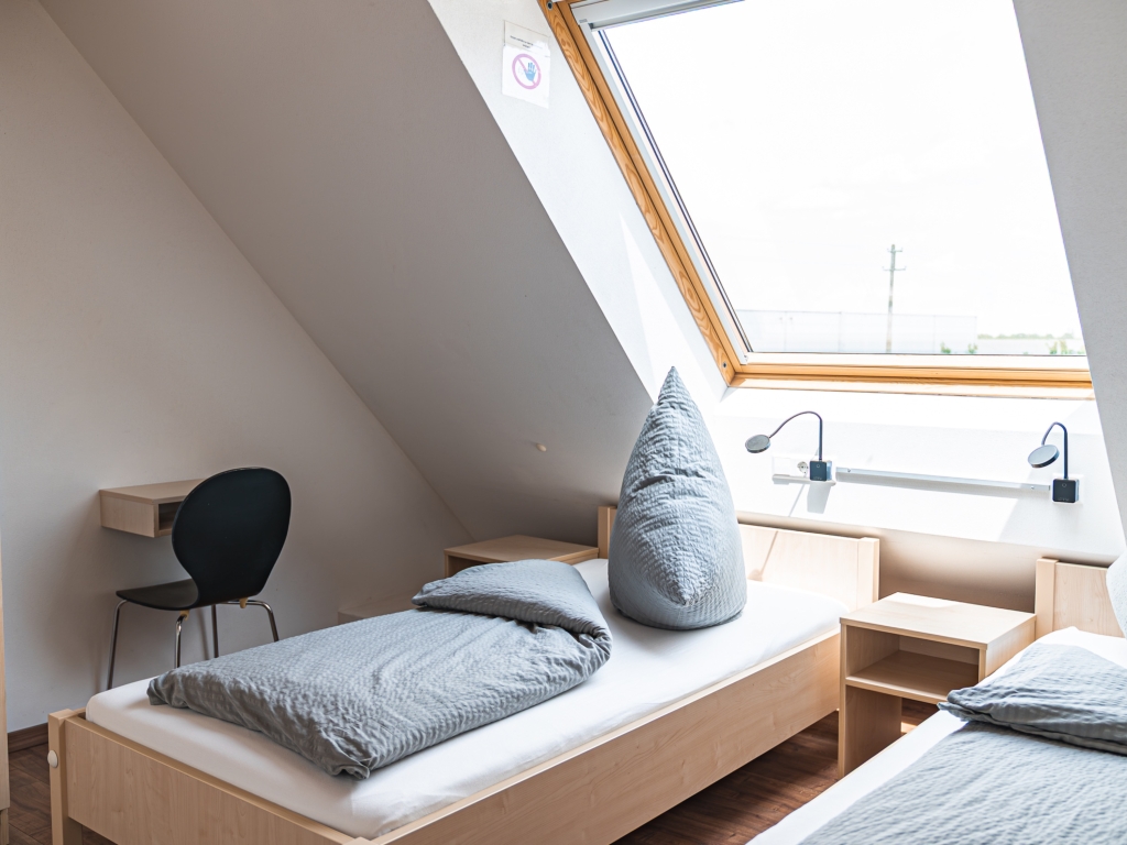 Ferienwohnung 3: Schlafzimmer mit Dachfenster, Einzelbett, Nachttisch und kleinem Schreibtisch mit Stuhl