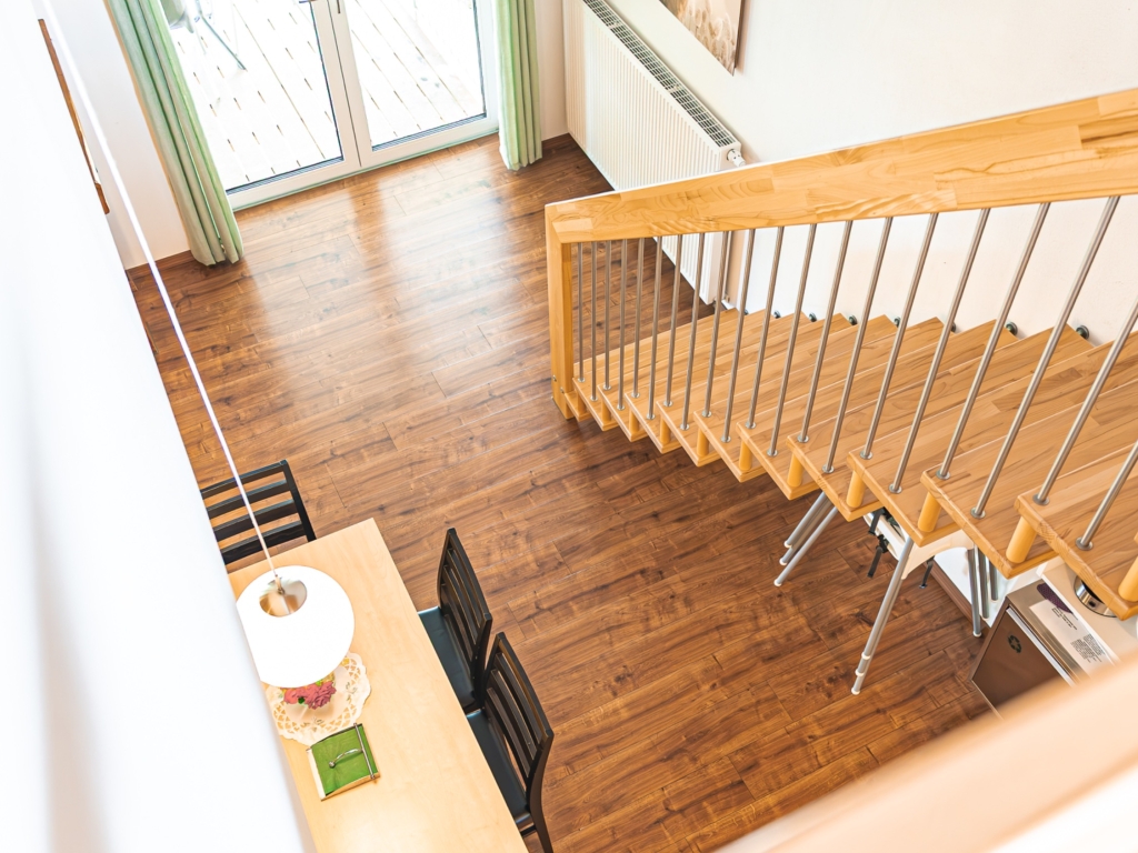 Ferienwohnung 3: Blick von der Galerie über die Holztreppe in den Wohnbereich mit Esstisch