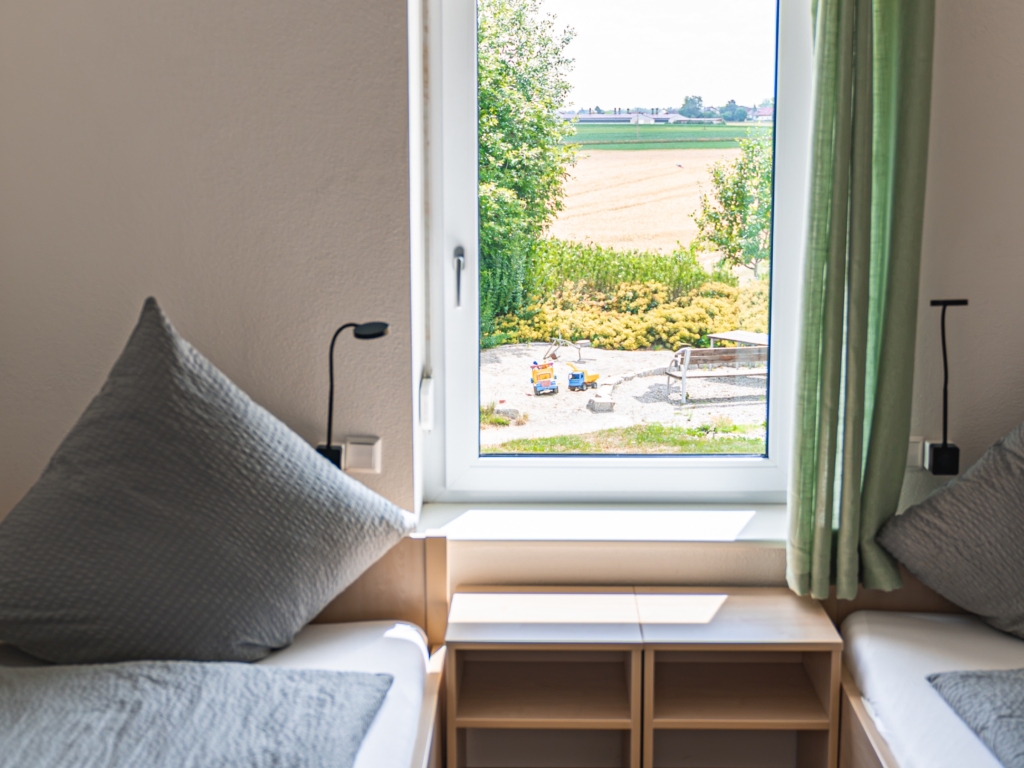 Ferienwohnung 4: Zwei Einzelbetten mit Nachttisch dazwischen vor einem Fenster mit Blick ins Grüne