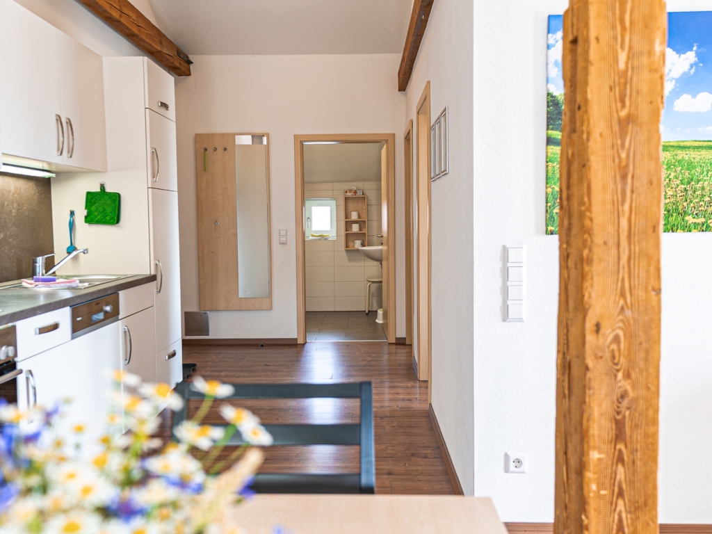 Ferienwohnung 4: Blick durch den Wohnbereich in den Flur mit Holzbalken und Esstisch im Vordergrund