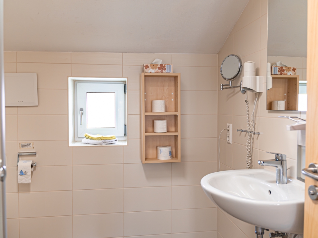 Ferienwohnung 4: Badezimmer mit Waschbecken, Kosmetikspiegel, Wandregal und Fenster