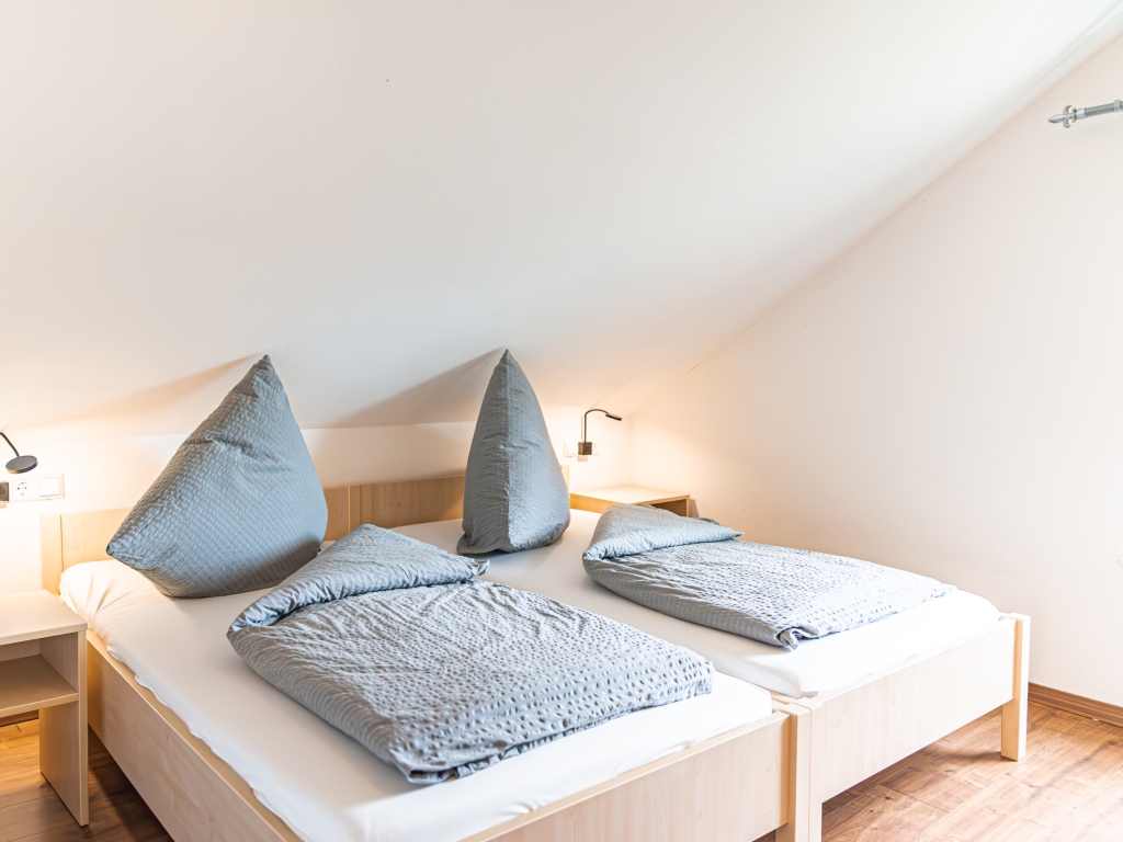 Ferienwohnung 5: Schlafzimmer mit zwei Betten, Leselampen an der Wand und Dachschräge