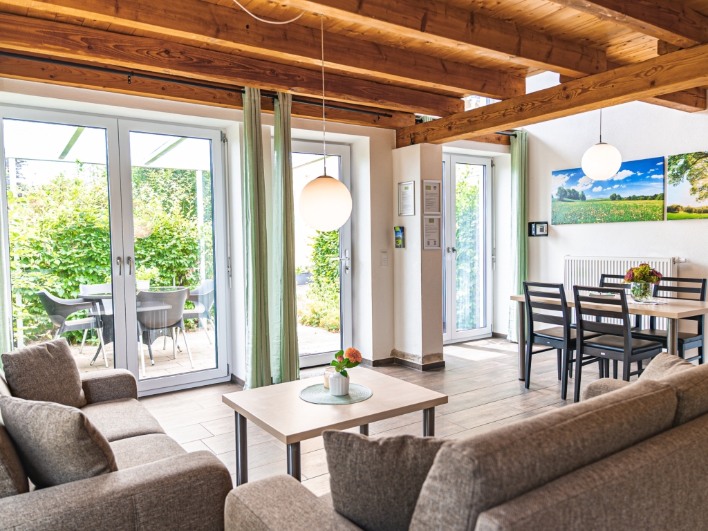 Ferienwohnung 7: Wohn-Essbereich mit zwei Sofas, Couchtisch, Esstisch und Terrassentüren mit Blick auf die Terrasse
