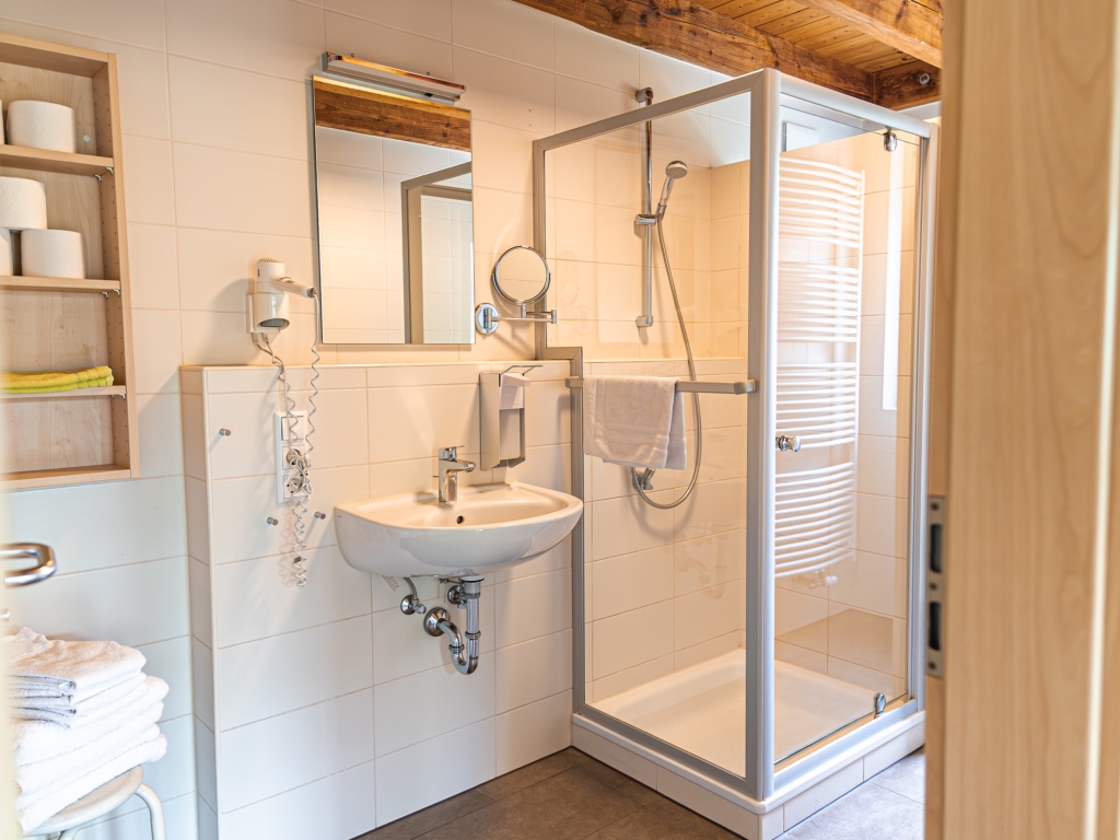 Ferienwohnung 7: Badezimmer mit Duschkabine, Waschbecken, Spiegel, Wandregal und Handtüchern