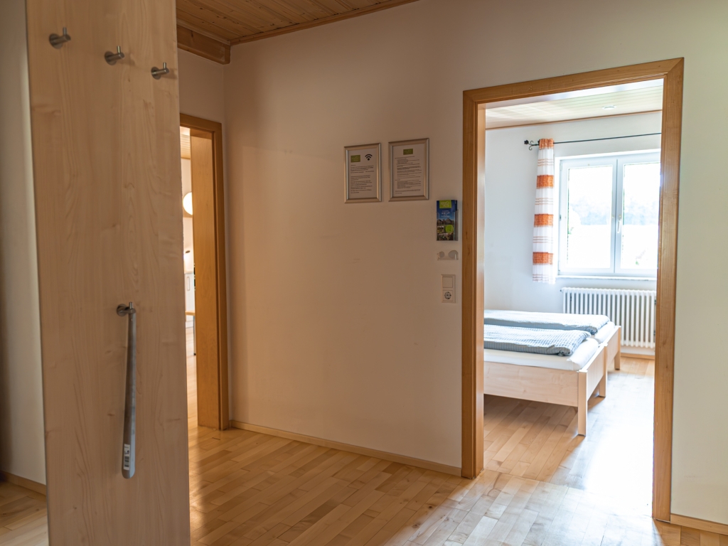 Ferienwohnung 8: Heller Flur mit Holzboden und Blick durch die offene Tür in ein Schlafzimmer