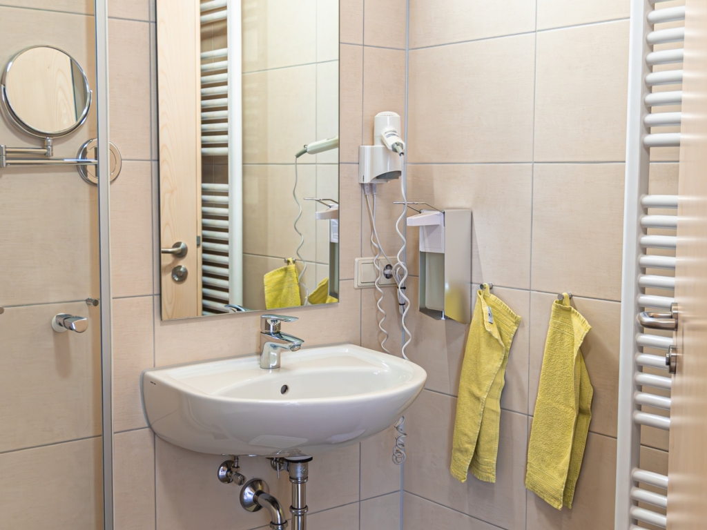 Ferienwohnung 9: Badezimmer mit Waschbecken, Spiegel, Handtuchheizkörper und gelben Handtüchern