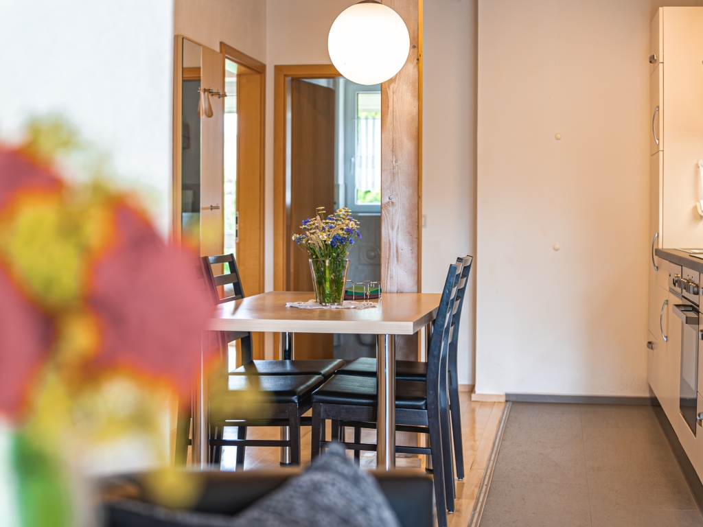 Ferienwohnung 9: Essbereich mit Holztisch und Stühlen, dahinter die Küchenzeile und eine Hängelampe